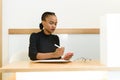 Beautiful young African or black American woman texting on mobile cellphone telephone in office Royalty Free Stock Photo