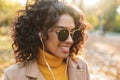 Beautiful young african happy woman walking outdoors in a spring park listening music with earphones Royalty Free Stock Photo