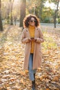 Beautiful young african happy woman walking outdoors in a spring park using mobile phone listening music with earphones Royalty Free Stock Photo