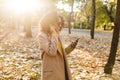 Beautiful young african happy woman walking outdoors in a spring park using mobile phone listening music with earphones Royalty Free Stock Photo