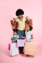Beautiful young African mother and two litlle cute daughters in casual outfits, standing satisfied with shopping bags in