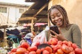 beautiful young african woman in a local african market viewing content on her phone feeling surprised Royalty Free Stock Photo