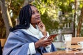 Beautiful Afro American woman listening to music on her cell phone in a cafe. Royalty Free Stock Photo