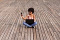 beautiful young afro american woman using laptop, Sitting on wood floor and smiling. wood background. Lifestyle outdoors Royalty Free Stock Photo