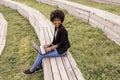 Beautiful young afro american woman using laptop, Sitting on wood stairs and smiling. wood background. Lifestyle outdoors Royalty Free Stock Photo