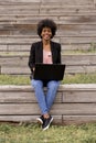 Beautiful young afro american woman using laptop, Sitting on wood stairs and smiling. wood background. Lifestyle outdoors Royalty Free Stock Photo