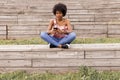 Beautiful young afro american woman using mobile phone, Sitting on wood stairs and smiling. wood background. Lifestyle outdoors Royalty Free Stock Photo