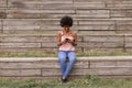 Beautiful young afro american woman using mobile phone, Sitting on wood stairs and smiling. wood background. Lifestyle outdoors Royalty Free Stock Photo