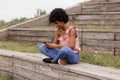 Beautiful young afro american woman using mobile phone, Sitting on wood stairs and smiling. wood background. Lifestyle outdoors Royalty Free Stock Photo