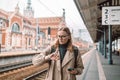 Beautiful young angry scared girl looking at her watch at the train station, holiday travel concept. Royalty Free Stock Photo