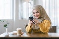 Beautiful young arab muslim woman wear hijab head scarf and using mobile phone in cafe. Royalty Free Stock Photo