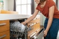 Beautiful young arab woman using dishwasher machine in modern kitchen Royalty Free Stock Photo