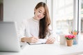 Beautiful young Asia woman smiling and writing on note book Royalty Free Stock Photo