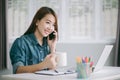 Asia woman working with smart phone and laptop in living room Royalty Free Stock Photo