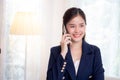 Beautiful young asian adviser or business woman talking on smartphone and smile while relax in the living room. Royalty Free Stock Photo