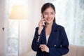 Beautiful young asian adviser or business woman talking on smartphone and smile while relax in the living room. Royalty Free Stock Photo