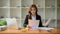 A beautiful young Asian businesswoman focuses on examining financial reports at her desk Royalty Free Stock Photo