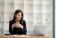 Beautiful young Asian businesswoman smiling holding a coffee mug and laptop working at the office. Royalty Free Stock Photo