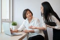 A beautiful young Asian businesswoman is talking with a senior female colleague in the office Royalty Free Stock Photo