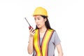 Beautiful young asian construction female worker in yellow helmet and reflective vest and using walkie talkie for talking with Royalty Free Stock Photo