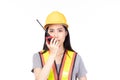 Beautiful young asian construction female worker in yellow helmet and reflective vest and using walkie talkie for talking with Royalty Free Stock Photo