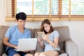 Beautiful young asian couple cheerful freelance working with man using laptop and woman using tablet on couch Royalty Free Stock Photo