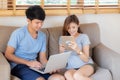 Beautiful young asian couple cheerful freelance working with man using laptop and woman using tablet on couch Royalty Free Stock Photo