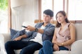 Beautiful young asian couple holding remote and watching tv or video streaming on sofa with relax and happy in living room at home Royalty Free Stock Photo