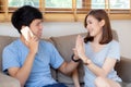 Beautiful young asian couple man and woman gesture high five together while man talking smart mobile phone on sofa Royalty Free Stock Photo