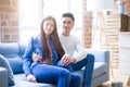 Beautiful young asian couple relaxing together sitting on the sofa arround cardboard boxes, happy moving to a new house Royalty Free Stock Photo