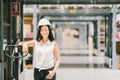 Beautiful young Asian engineer or technician woman smiling, warehouse or factory blur background, industry or logistic concept