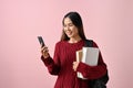 Beautiful Asian female college student using her smartphone, and standing over a pink background Royalty Free Stock Photo