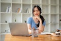 A beautiful Asian female college student smiles while listening to music through her headphones Royalty Free Stock Photo