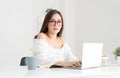 Beautiful young Asian female student using laptop and looking at camera while sitting in living room at home. Education, Royalty Free Stock Photo