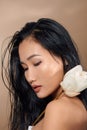 Beautiful young asian girl with natural make-up and wet hair posing in the studio on a beige background Royalty Free Stock Photo
