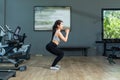 Beautiful young asian girl is wearing workout clothes and doing squat exercises at the fitness center Royalty Free Stock Photo