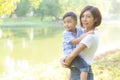 Beautiful young asian mother carrying little boy in the park, asia woman happy having son and hug kid Royalty Free Stock Photo