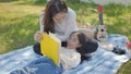 Beautiful young asian mother and daughter doing picnic and reading tale in yellow books at green park. Royalty Free Stock Photo