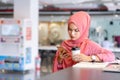 Beautiful young asian muslim business woman in pink hijab and casual wear working with laptop and business report at creative co-