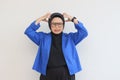 beautiful young asian muslim woman, wearing glasses and blue blazer is angry holding her head Royalty Free Stock Photo