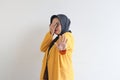 Beautiful young Asian Muslim woman, wearing glasses and yellow blazer covering 1 side of face with hand Royalty Free Stock Photo