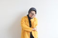 Beautiful young Asian Muslim woman, wearing glasses and yellow blazer covering 1 side of face with hand Royalty Free Stock Photo