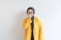 Beautiful young Asian Muslim woman, wearing glasses and yellow blazer with scared face expression Royalty Free Stock Photo