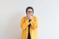 beautiful young Asian Muslim woman, wearing glasses and yellow blazer with shocked expression while covering mouth Royalty Free Stock Photo