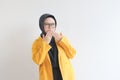 beautiful young Asian Muslim woman, wearing glasses and yellow blazer with shocked expression while covering mouth Royalty Free Stock Photo