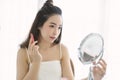 Beautiful young Asian woman applying red lip tint while sitting at table and looking at mirror. Korean girl blogger with excellent