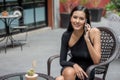 Beautiful young asian woman in black dress sitting in the coffee cafe  calling with smartphone . happy elegant lady sitting on Royalty Free Stock Photo