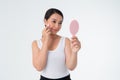 Beautiful young Asian woman cleaning her skin with a cotton pad and holding Makeup mirror,  isolated over white background Royalty Free Stock Photo