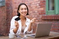 Beautiful young asian woman with credit card, sitting near laptop and smiling, paying bills, shops online, order smth on Royalty Free Stock Photo