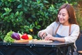 A beautiful woman cutting and chopping carrot by knife on wooden board with mixed vegetables in a tray Royalty Free Stock Photo